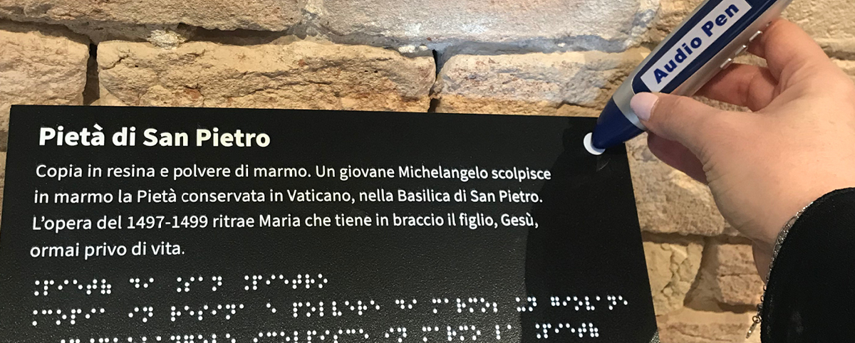 Una persona attiva l'audiopen appoggiandola sul bollino presente sulla didascalia del museo.